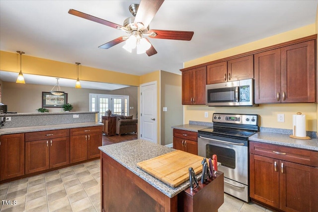 kitchen with ceiling fan, stainless steel appliances, open floor plan, a center island, and decorative light fixtures