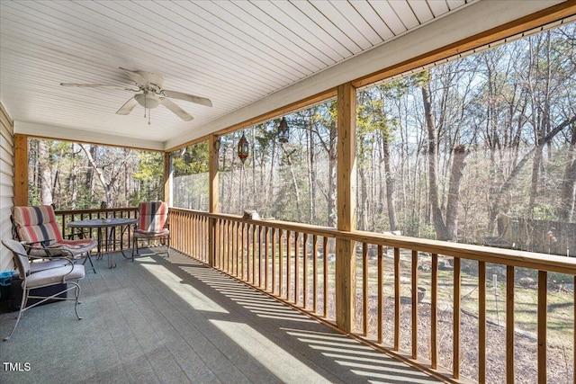 unfurnished sunroom featuring ceiling fan and a view of trees