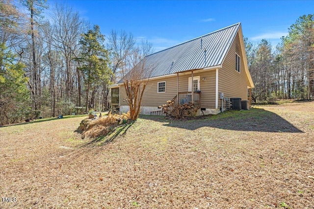 view of property exterior featuring metal roof, central AC, a yard, and crawl space