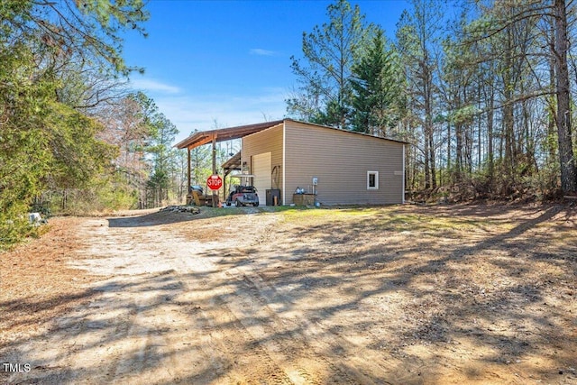 view of side of property featuring a garage, driveway, an outdoor structure, and an outbuilding