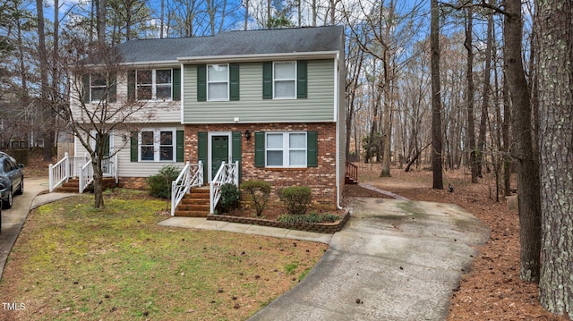 colonial-style house with driveway, a front yard, and brick siding