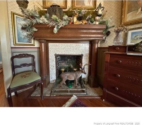 sitting room with wallpapered walls, wood finished floors, and a tile fireplace