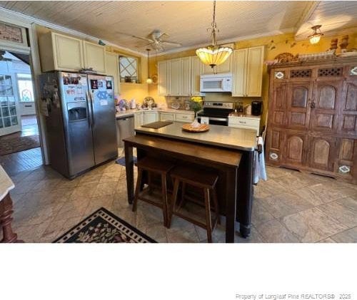 kitchen with ceiling fan, a kitchen island, appliances with stainless steel finishes, decorative light fixtures, and light countertops