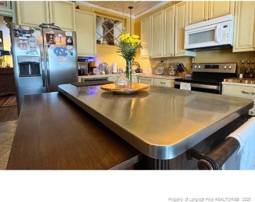 kitchen featuring dark tile patterned flooring, a kitchen island, appliances with stainless steel finishes, a breakfast bar area, and pendant lighting