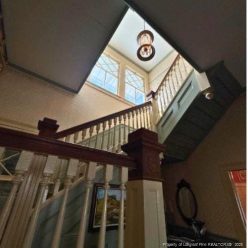 stairway with a towering ceiling and a chandelier