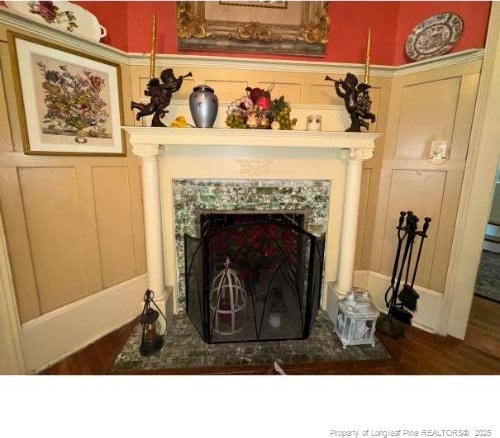 interior details featuring a fireplace, a decorative wall, and wood finished floors