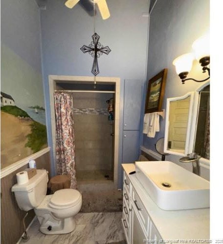 bathroom featuring tiled shower, toilet, ceiling fan, marble finish floor, and vanity