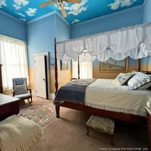 carpeted bedroom featuring ornamental molding, baseboards, and a ceiling fan