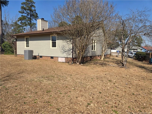 view of side of home with crawl space, central AC, a lawn, and a chimney