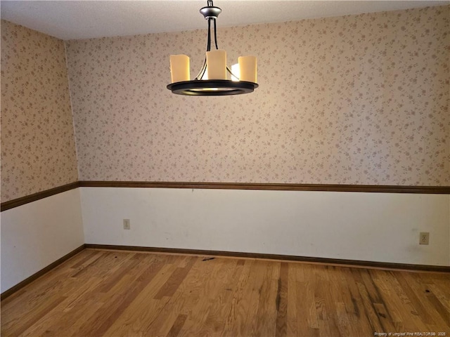 empty room with wallpapered walls, baseboards, and wood finished floors