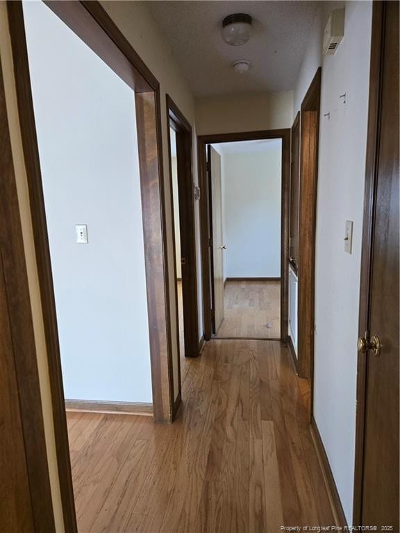 corridor with baseboards and wood finished floors