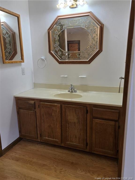 bathroom with wood finished floors, vanity, and baseboards