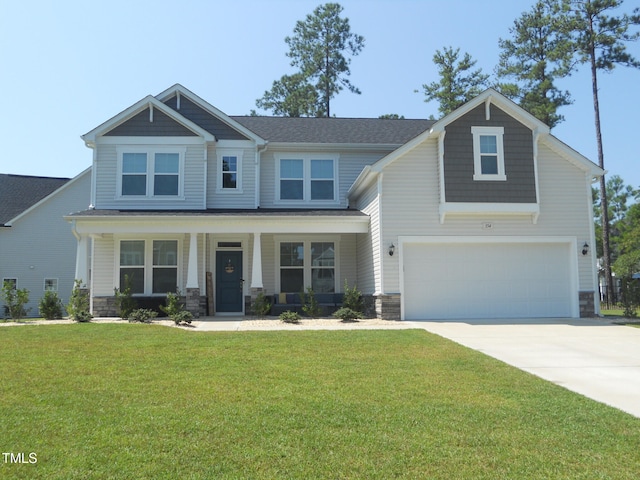 craftsman-style house with a porch, a front yard, stone siding, and driveway