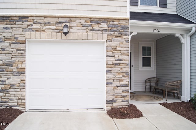 doorway to property featuring stone siding and a shingled roof