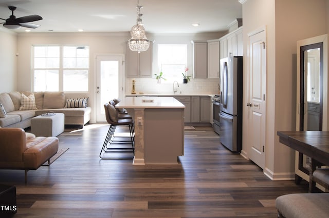 kitchen featuring ornamental molding, decorative backsplash, a sink, stainless steel appliances, and open floor plan