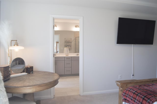 bedroom with baseboards, light colored carpet, and ensuite bathroom