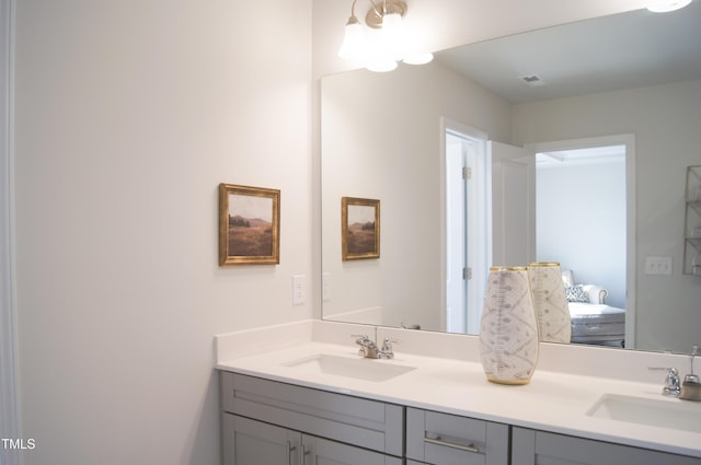 ensuite bathroom featuring double vanity, connected bathroom, and a sink