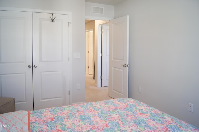 bedroom with a closet, visible vents, and light carpet