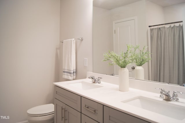 bathroom with double vanity, toilet, and a sink