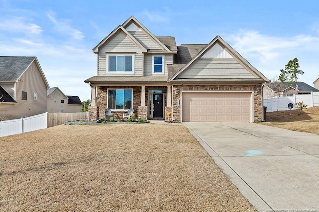 craftsman-style house featuring a porch, concrete driveway, a front yard, fence, and a garage