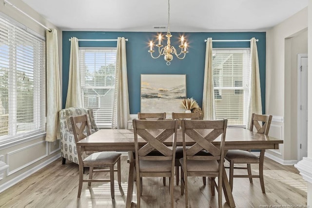 dining area with light wood-style floors, visible vents, baseboards, and a notable chandelier