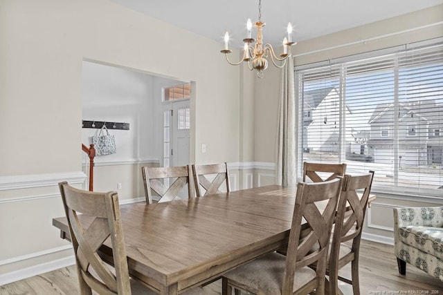 dining room with light wood-type flooring and an inviting chandelier