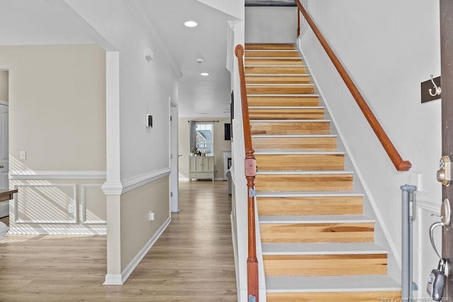 staircase featuring recessed lighting, a fireplace, wood finished floors, baseboards, and ornamental molding