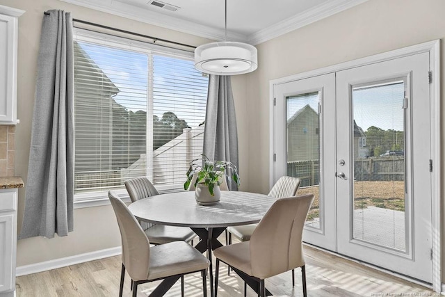 dining space with ornamental molding, french doors, light wood-style floors, and a healthy amount of sunlight