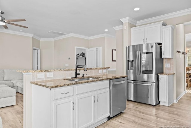 kitchen featuring a center island with sink, decorative backsplash, white cabinets, appliances with stainless steel finishes, and a sink