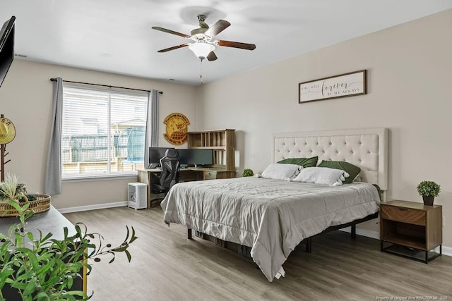 bedroom with ceiling fan, baseboards, and wood finished floors