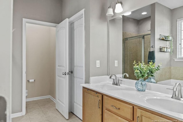 full bathroom with toilet, a stall shower, double vanity, and a sink