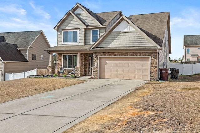 craftsman inspired home featuring a garage, driveway, covered porch, and fence