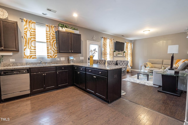 kitchen featuring dark wood finished floors, visible vents, stainless steel dishwasher, a sink, and a peninsula