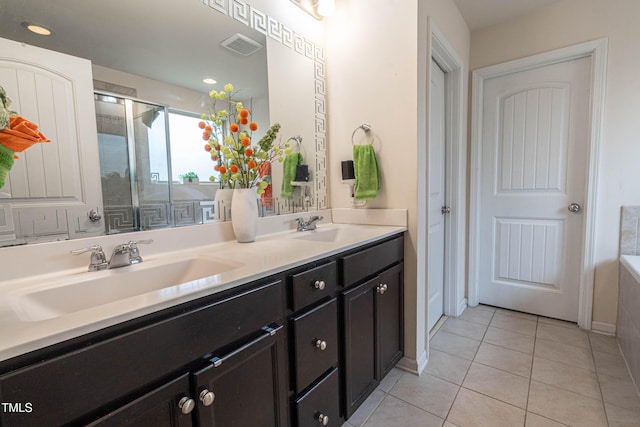 bathroom featuring a shower stall, double vanity, a sink, and tile patterned floors