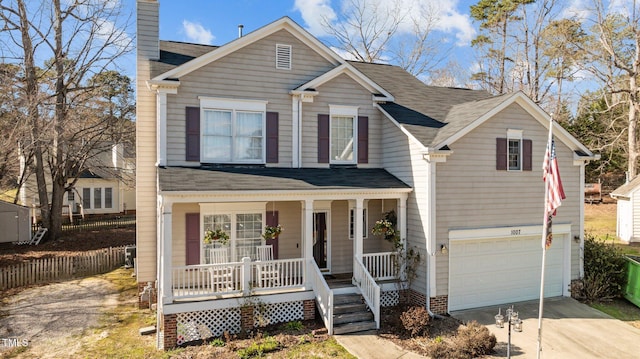 traditional-style home with driveway, a shingled roof, a chimney, an attached garage, and covered porch