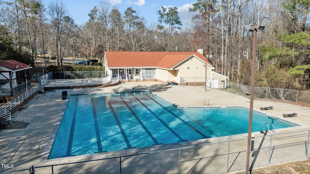 community pool with fence and a patio