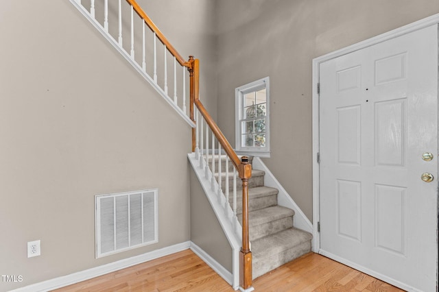 entrance foyer with visible vents, stairway, and wood finished floors