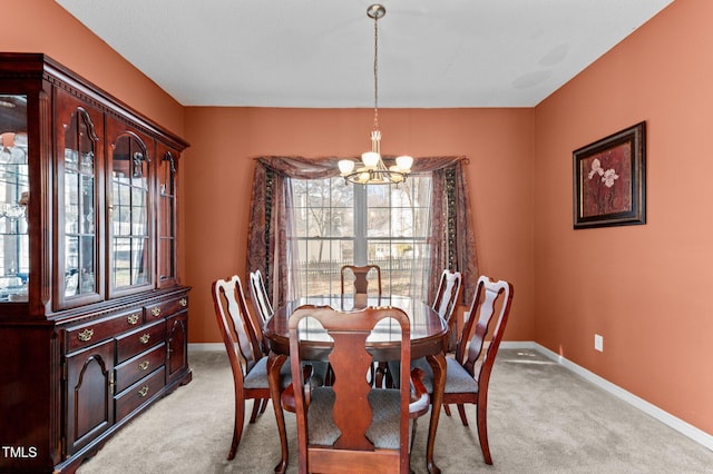 dining room with a chandelier, light carpet, and baseboards