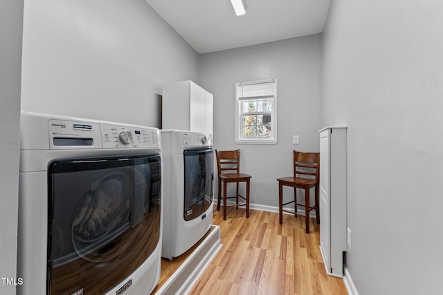 washroom featuring light wood finished floors, baseboards, and washer and clothes dryer