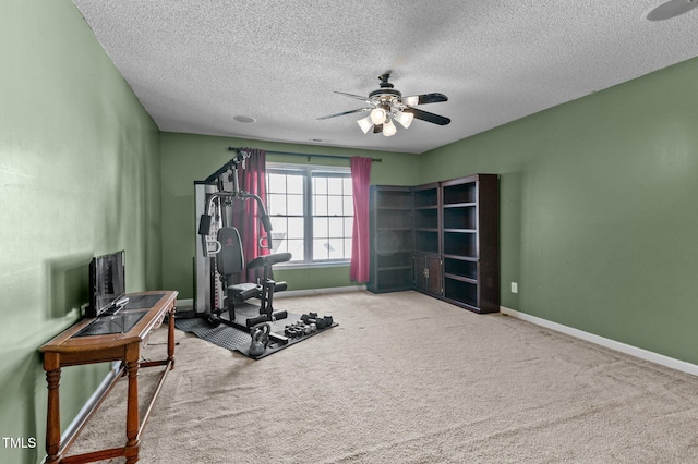 workout area featuring carpet flooring, ceiling fan, a textured ceiling, and baseboards