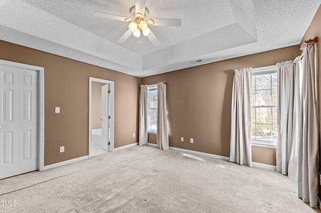 unfurnished bedroom featuring baseboards, a tray ceiling, a textured ceiling, and carpet flooring