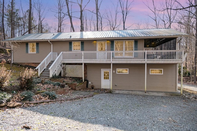 view of front of home featuring stairs, metal roof, and gravel driveway