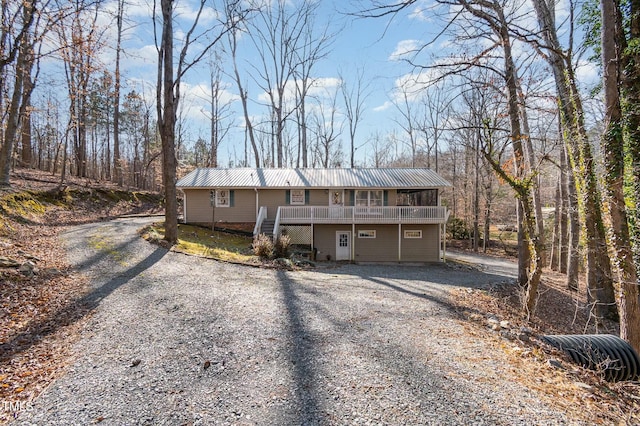 view of front facade with metal roof, driveway, and a wooden deck