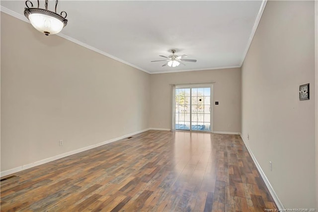 empty room featuring crown molding, baseboards, and wood finished floors