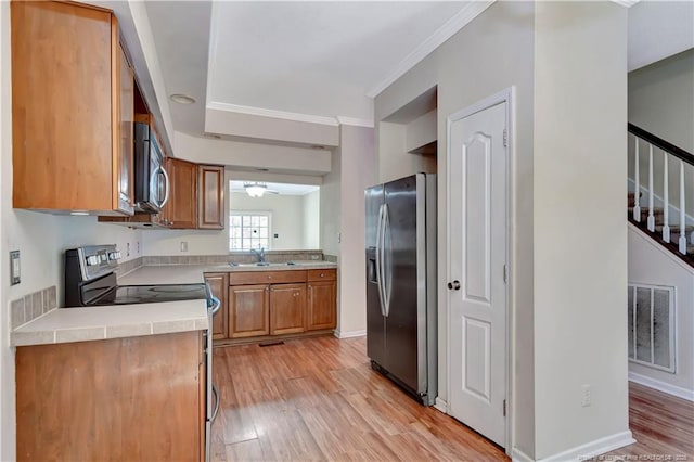 kitchen featuring light wood-style flooring, stainless steel appliances, a sink, visible vents, and light countertops