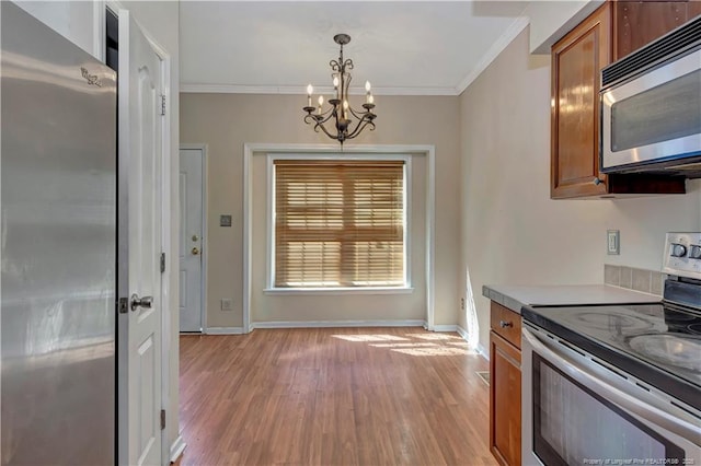 kitchen with brown cabinets, light wood-style flooring, appliances with stainless steel finishes, ornamental molding, and baseboards