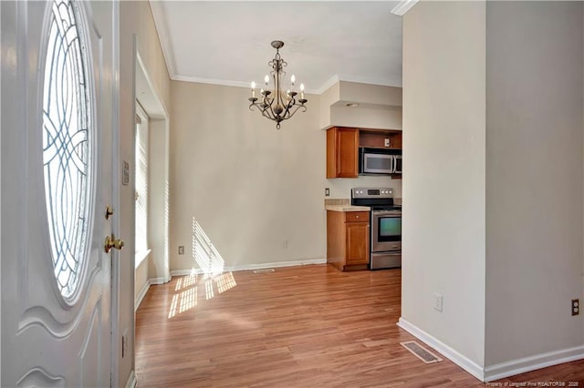 kitchen featuring brown cabinets, crown molding, visible vents, appliances with stainless steel finishes, and a chandelier