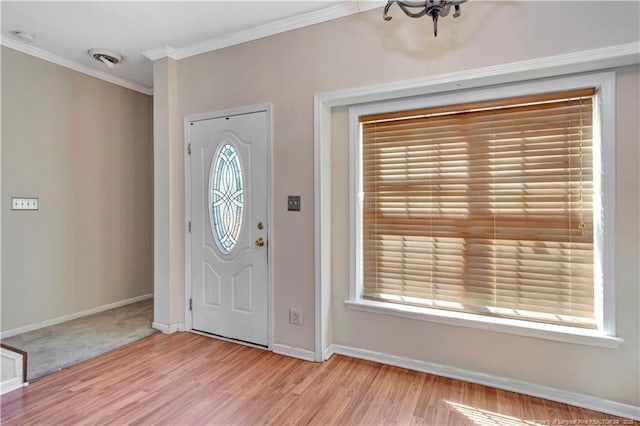 foyer featuring baseboards, wood finished floors, visible vents, and crown molding