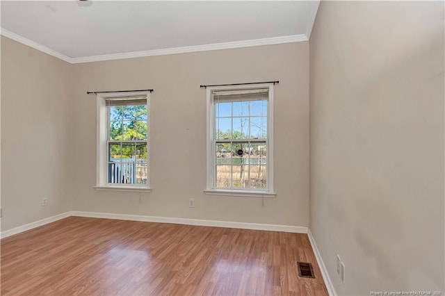 empty room with baseboards, ornamental molding, visible vents, and a healthy amount of sunlight