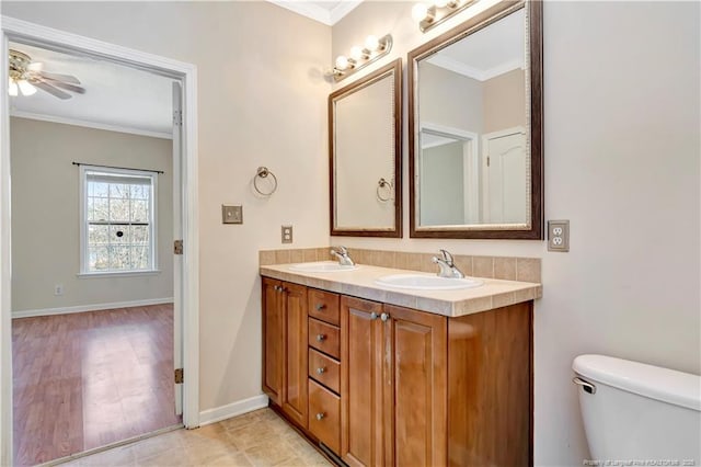 full bathroom with baseboards, double vanity, a sink, and crown molding